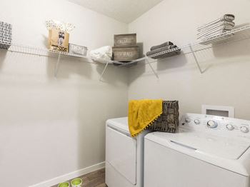 Full-sized washer and dryer in large laundry room with built-in shelving