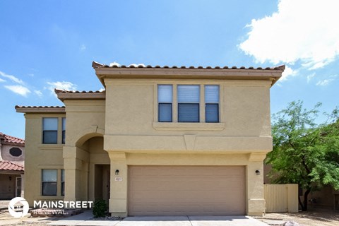 a beige house with a garage door and a blue sky