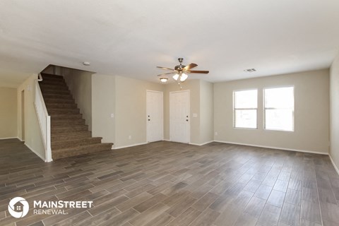 a living room with a staircase and a ceiling fan