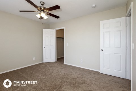a bedroom with a ceiling fan and a door to a closet