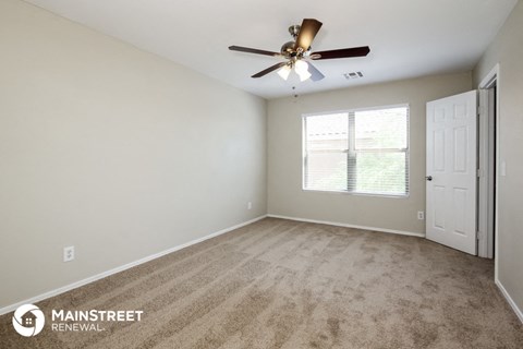 the spacious living room with carpeting and a ceiling fan