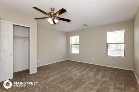 the spacious living room with closet and ceiling fan