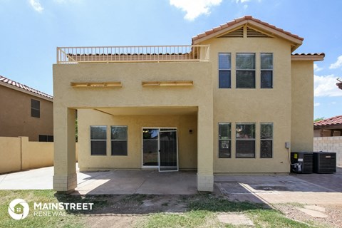 the front of a tan house with a garage and a driveway