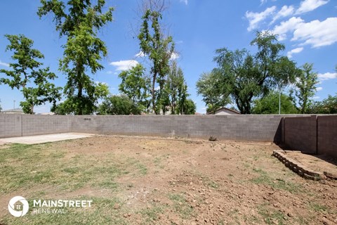 a back yard with a concrete wall and some trees