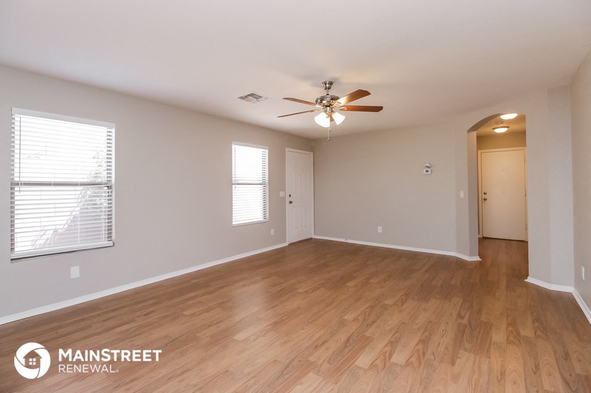 the spacious living room with wood flooring and ceiling fan