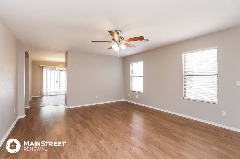 the living room and dining room with wood flooring and ceiling fan