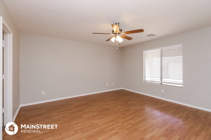 the spacious living room with wood flooring and a ceiling fan