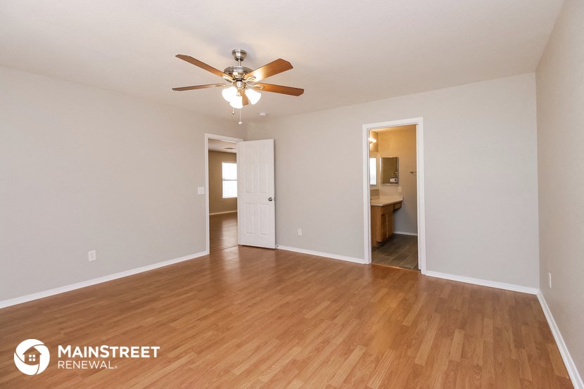 the living room and dining room with wood flooring and a ceiling fan