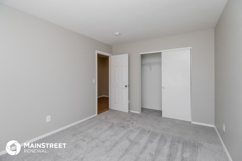 a master bedroom with a carpeted floor and a door to a closet