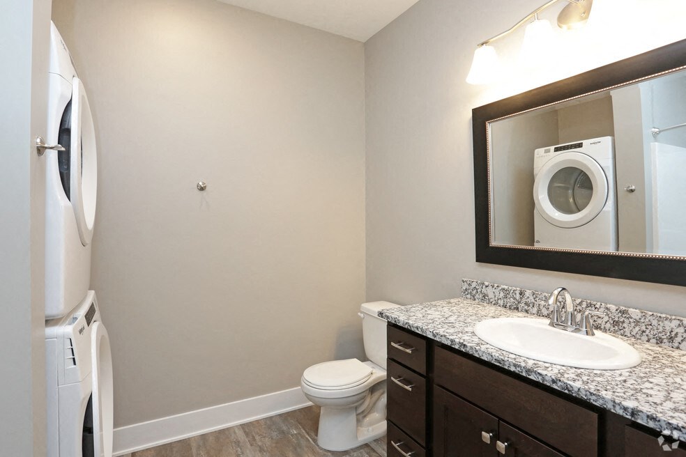 a bathroom with a toilet sink and mirror and a washing machine