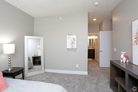 a bedroom with a bed and a mirror and a hallway to a bathroom