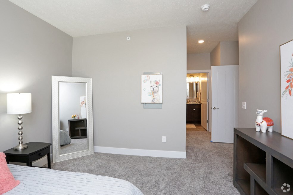 a bedroom with a bed and a mirror and a hallway to a bathroom