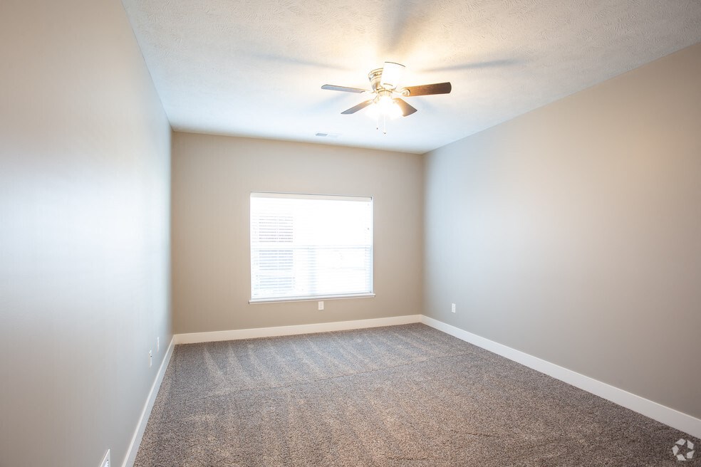 an empty room with a ceiling fan and a window