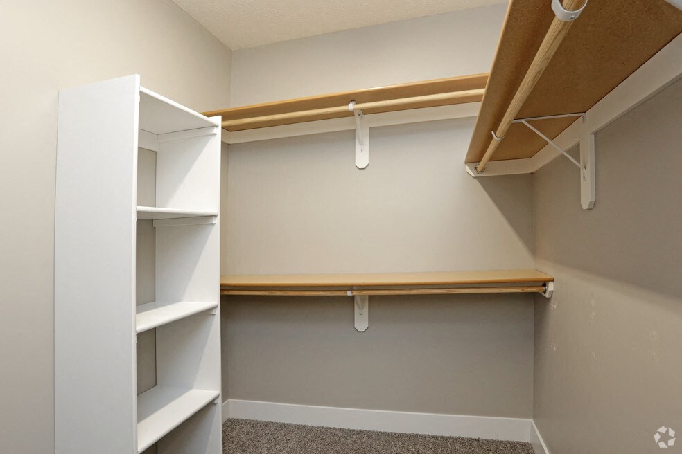 a walk in closet in a home with shelves and hooks