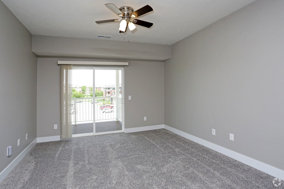 an empty living room with a ceiling fan and a window