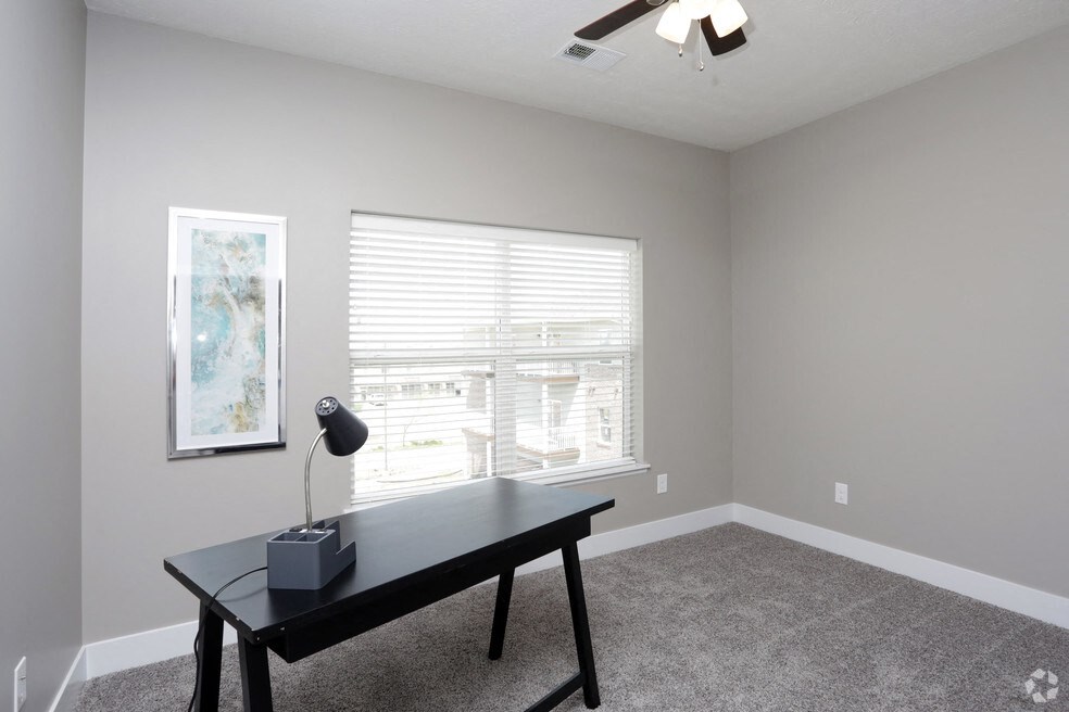 a home office with a desk and a large window