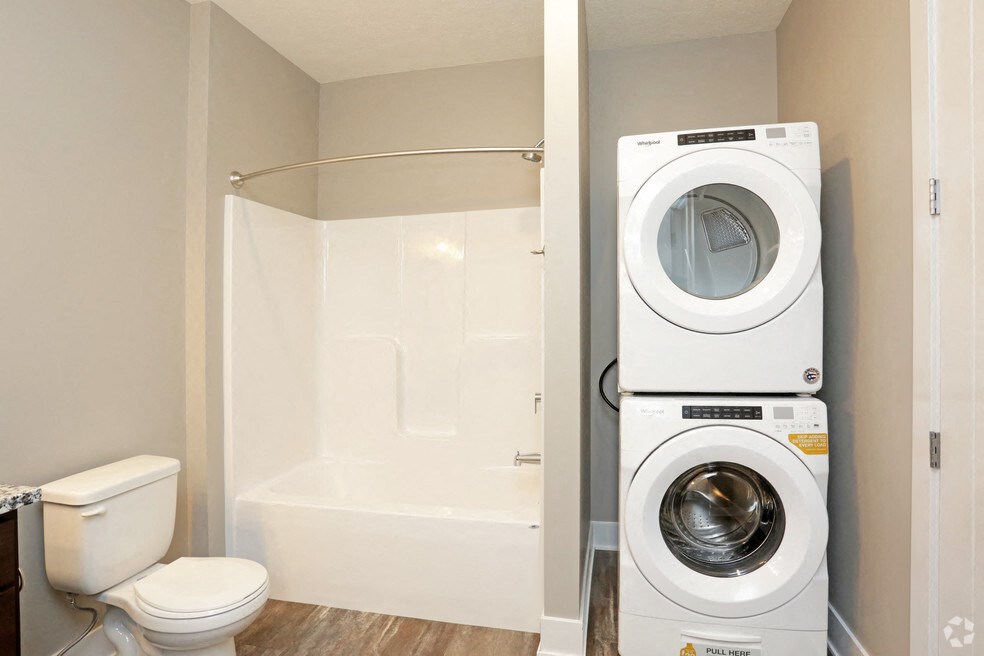 a washer and dryer in a bathroom next to a toilet and a shower