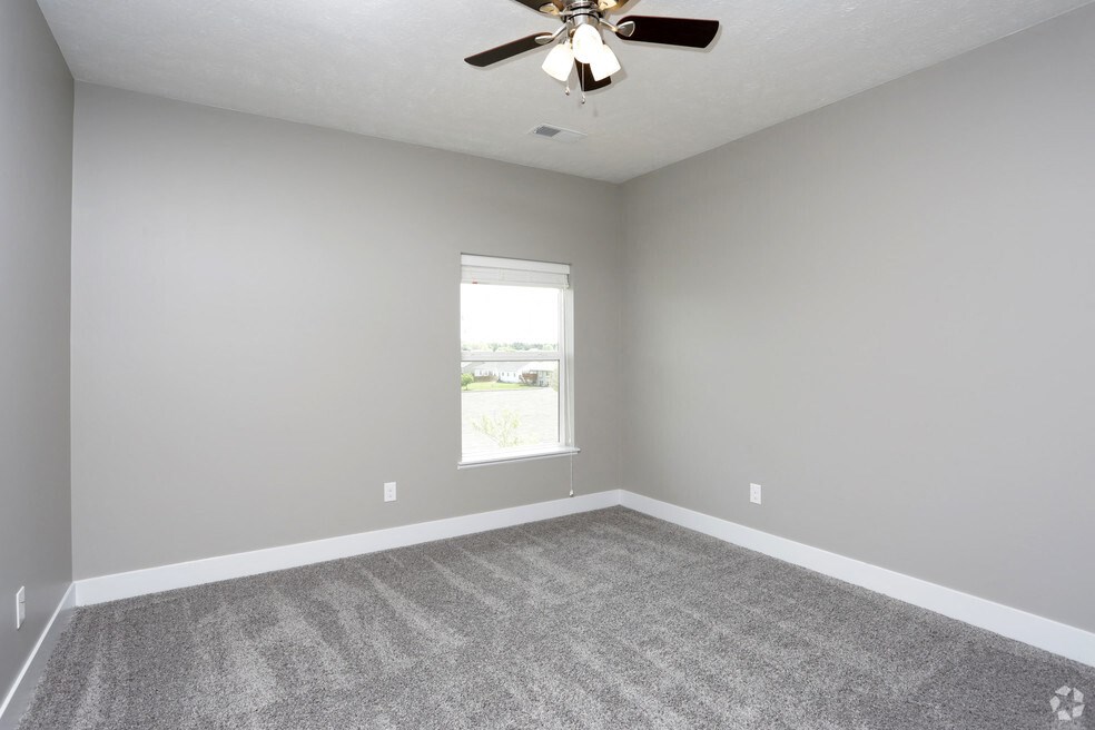 an empty living room with a ceiling fan and a window