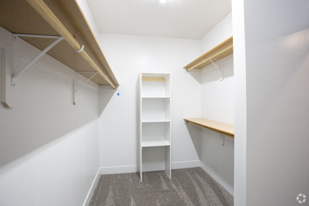 a walk in closet with a shelving unit and a shelf