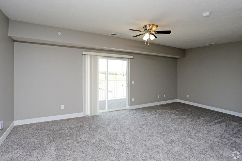 an empty living room with a ceiling fan and a window