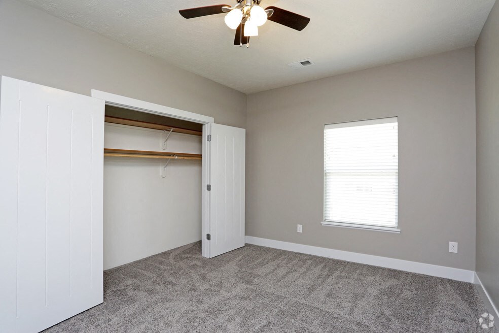 an empty bedroom with a closet and a ceiling fan