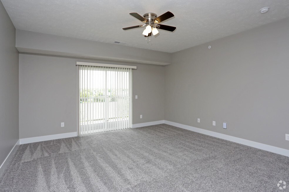 an empty living room with a ceiling fan and a window