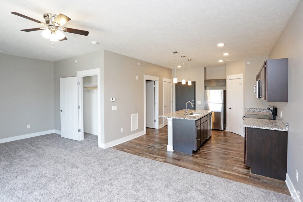 a living room with a kitchen and a ceiling fan