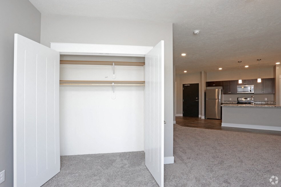 an empty living room with a white wall and a kitchen