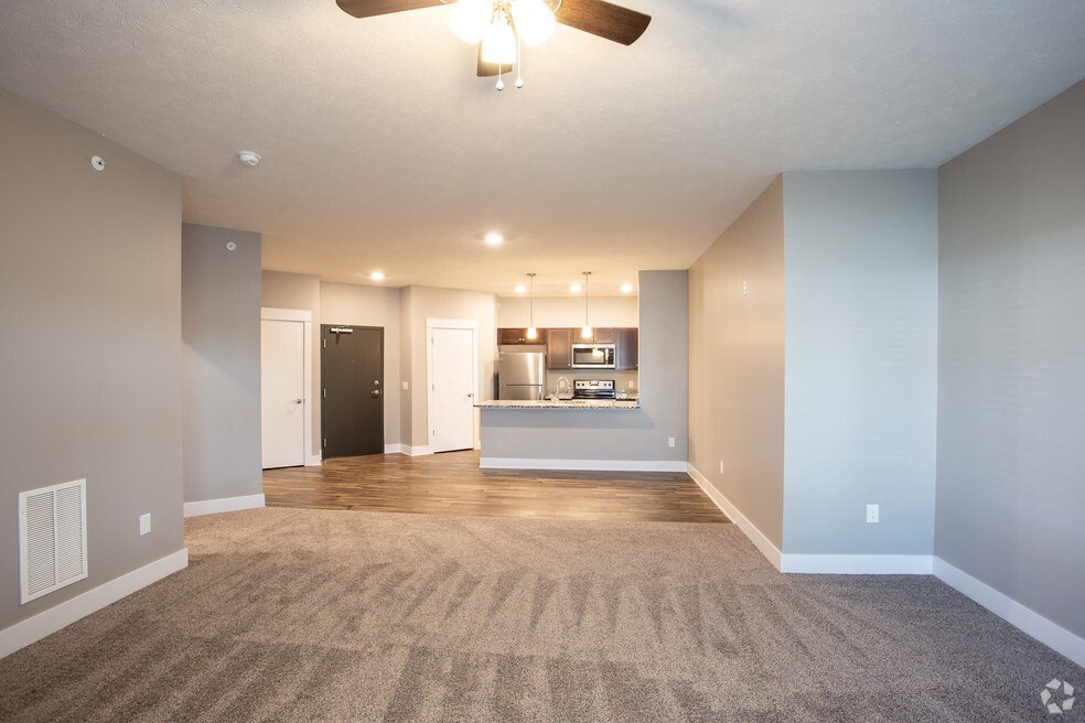 an empty living room and kitchen with a ceiling fan
