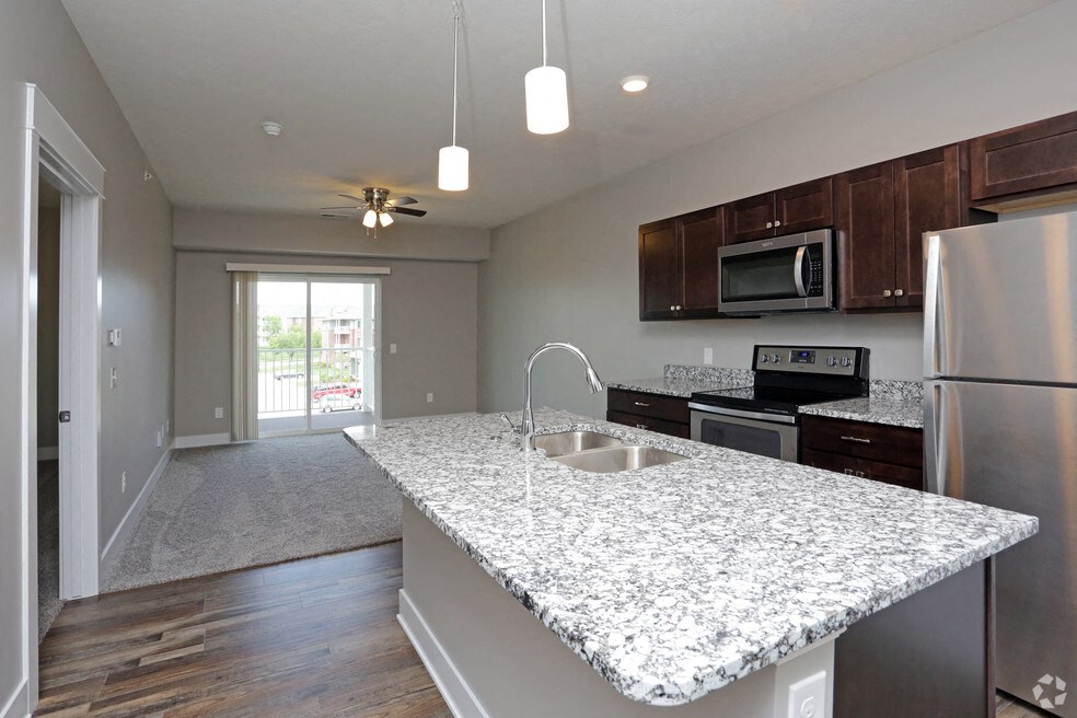 a kitchen with a marble counter top and a stainless steel refrigerator