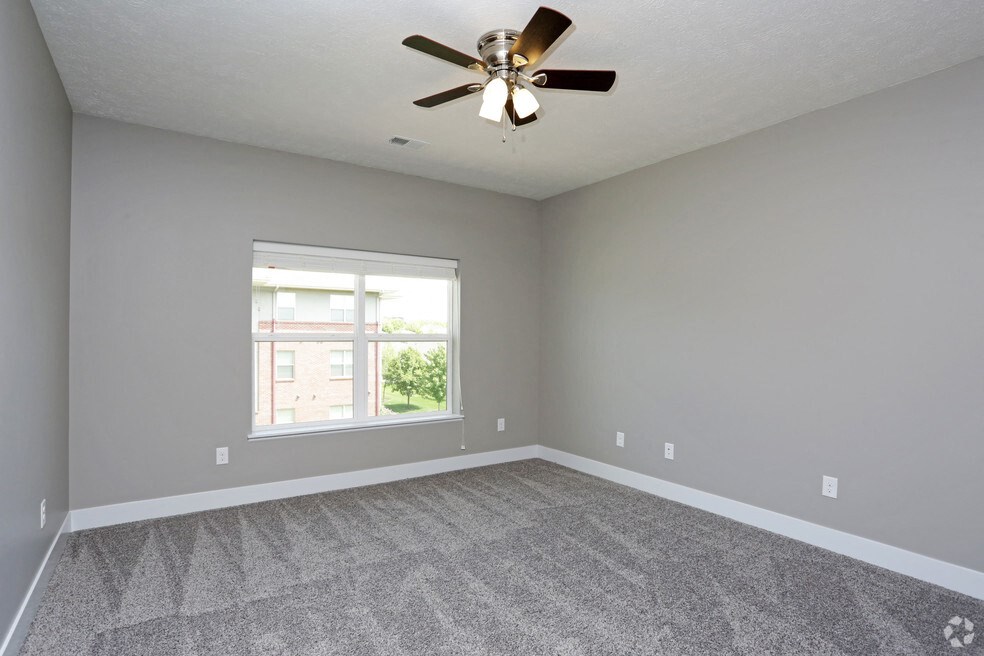 an empty living room with a ceiling fan and a window