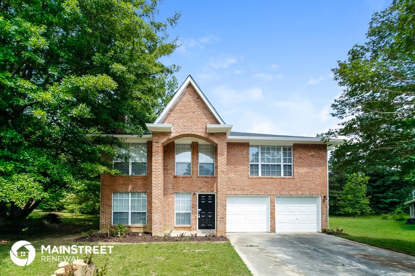 front view of a brick house with white garage doors