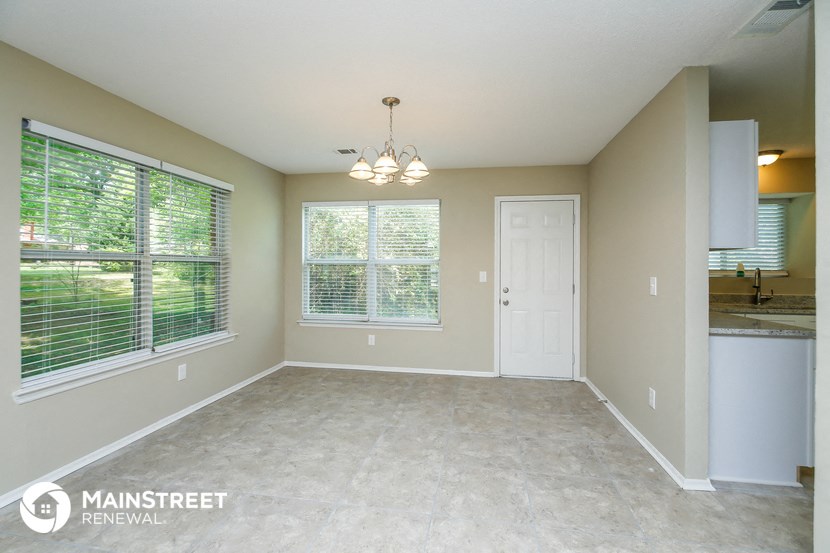 an empty dining room with large windows and a white door
