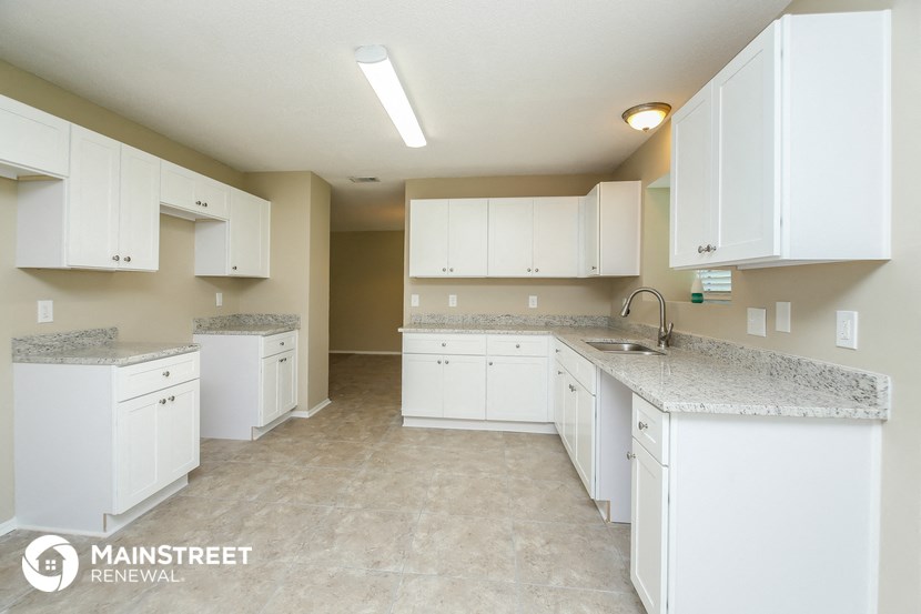 a large kitchen with white cabinets and granite counter tops