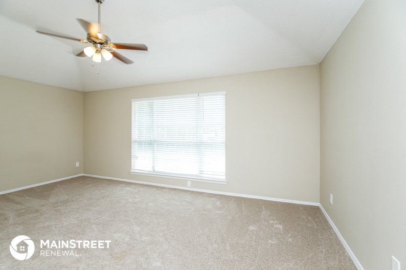 a bedroom with a ceiling fan and a large window