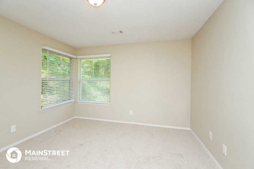 the spacious master bedroom has a large window and carpeted flooring