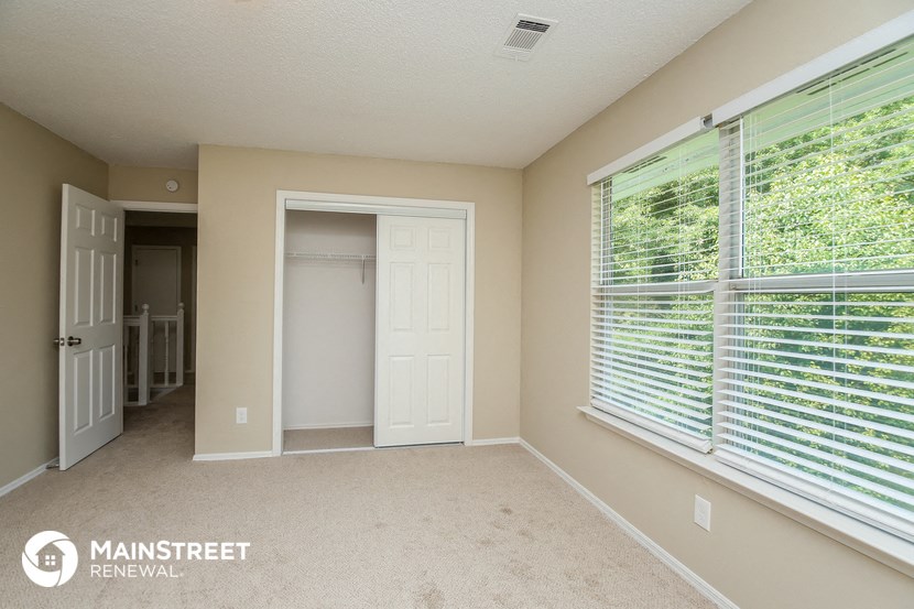 a bedroom with a large window and a door to a closet
