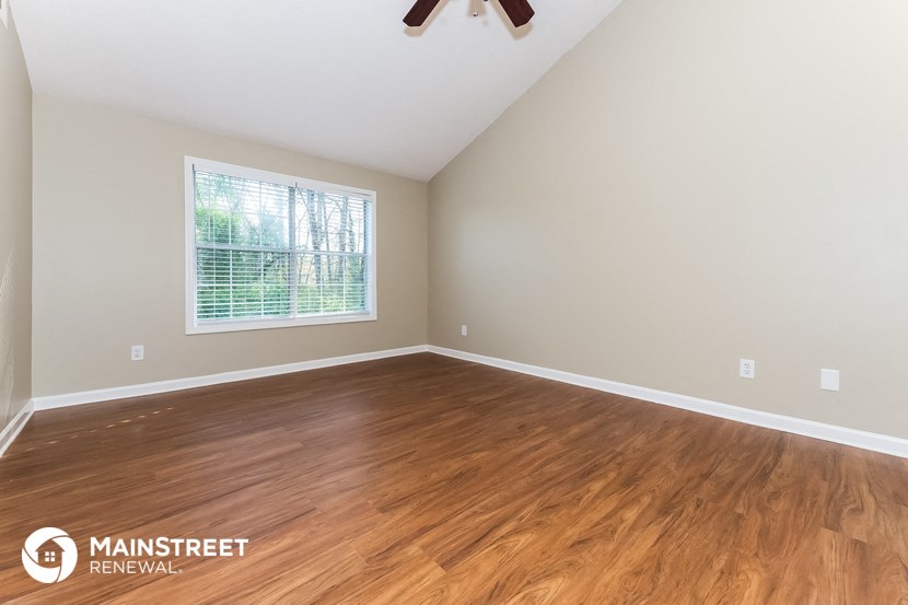 the living room of a home with wood flooring and a window