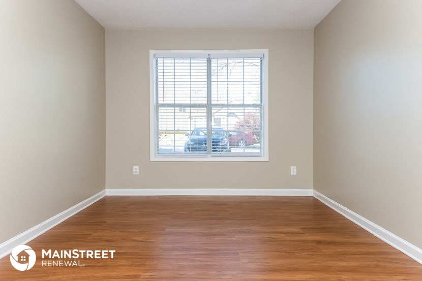 an empty room with wood floors and a window