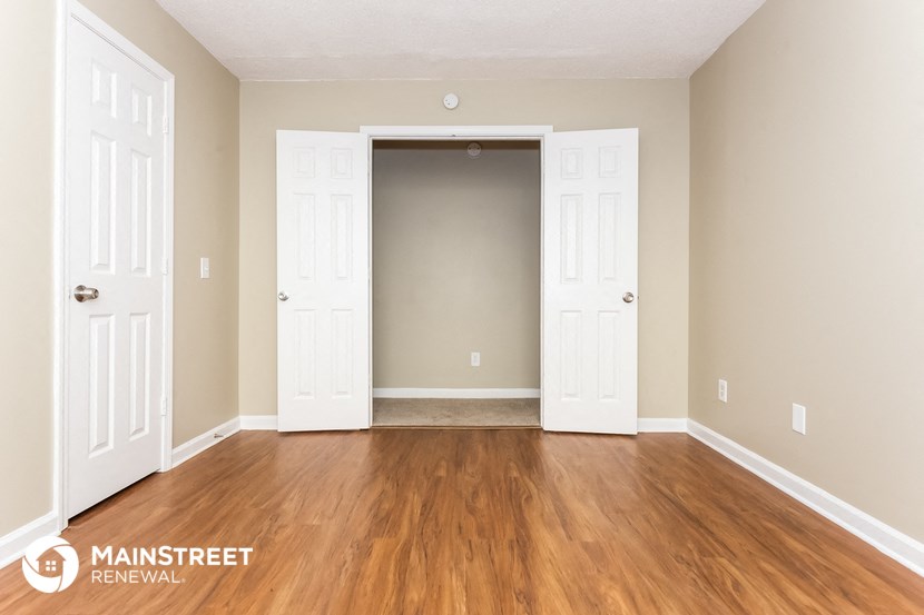 the living room of an apartment with wood floors and white doors