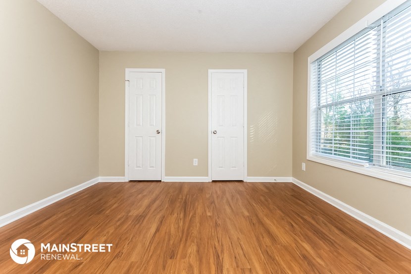the living room of a home with wood flooring and two doors