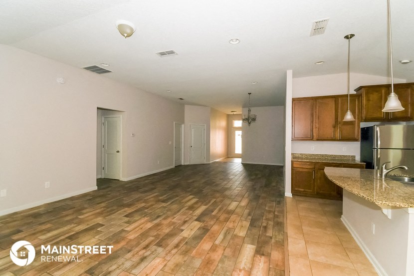 an open kitchen and living room with wood flooring and stainless steel appliances