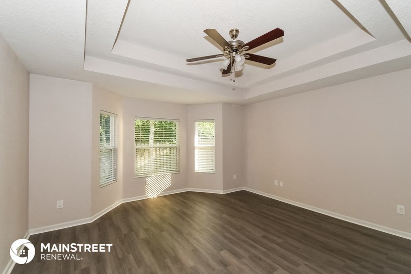 the living room of a home with wood floors and a ceiling fan