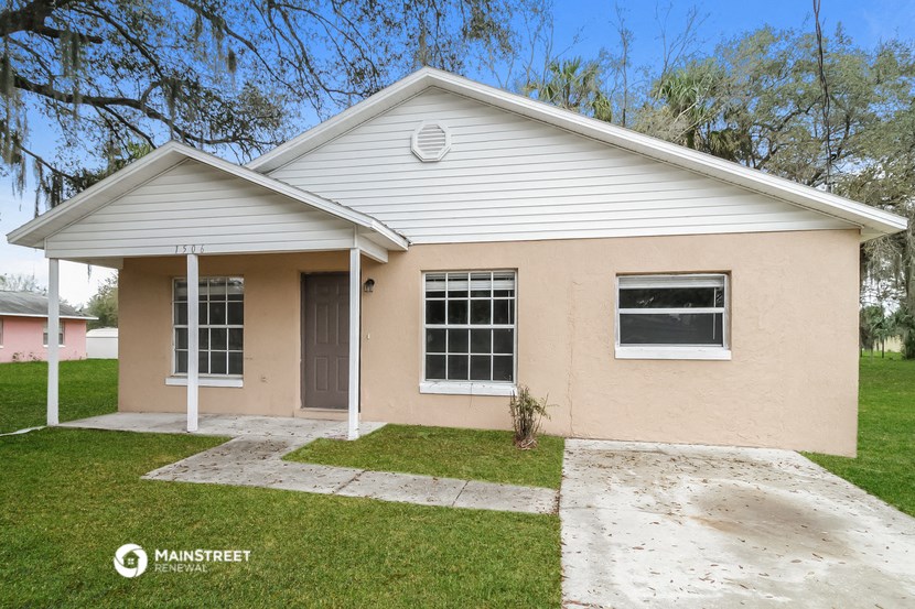 the front of a pink house with a lawn and trees