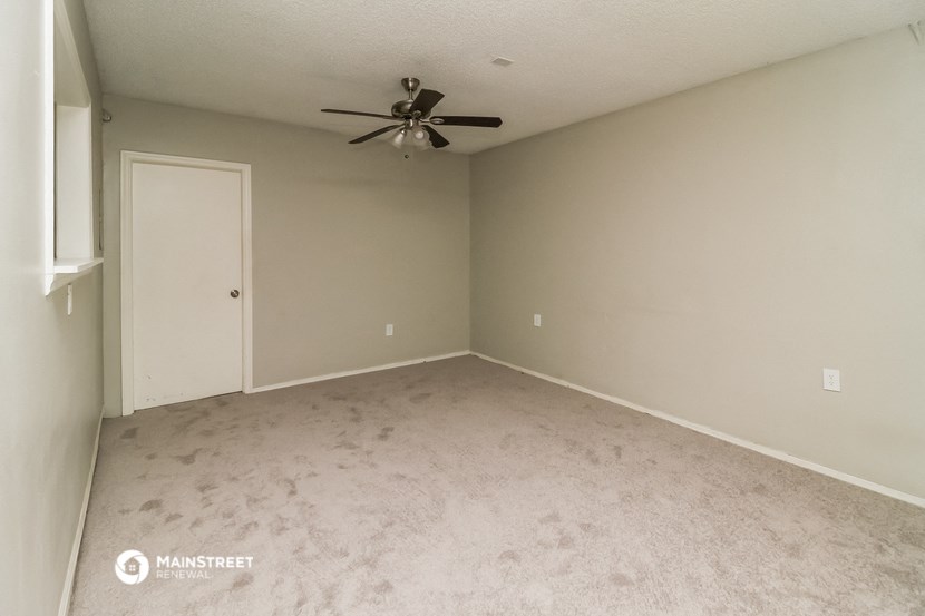 an empty living room with a ceiling fan