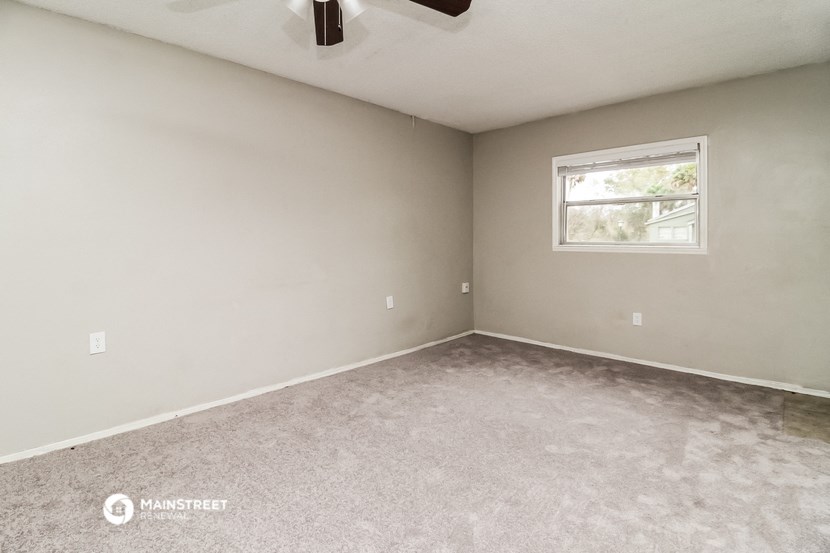the living room of an empty home with carpet and a window