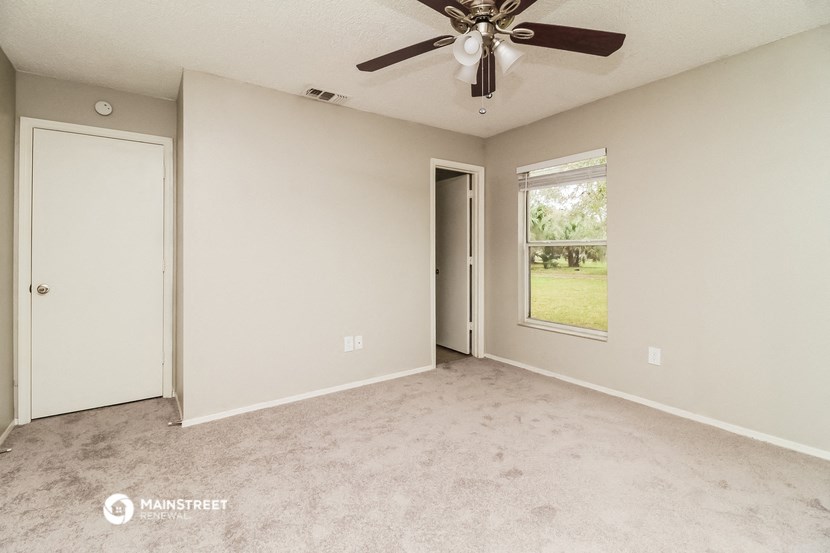an empty living room with a ceiling fan and a window