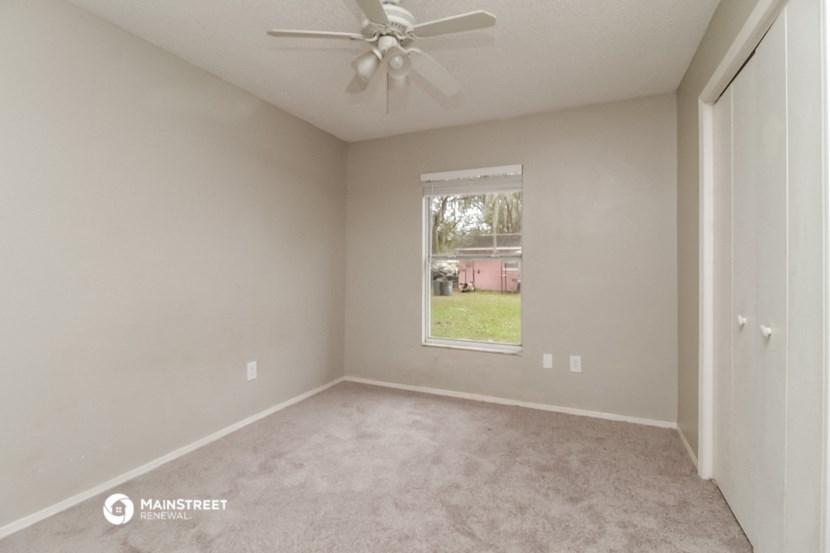 an empty room with a window and a ceiling fan