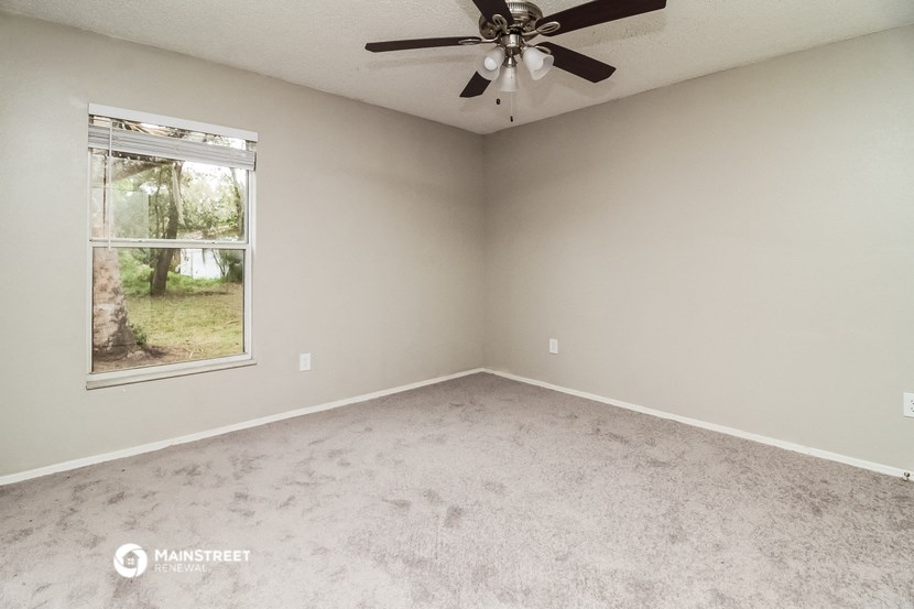 an empty room with a ceiling fan and a window