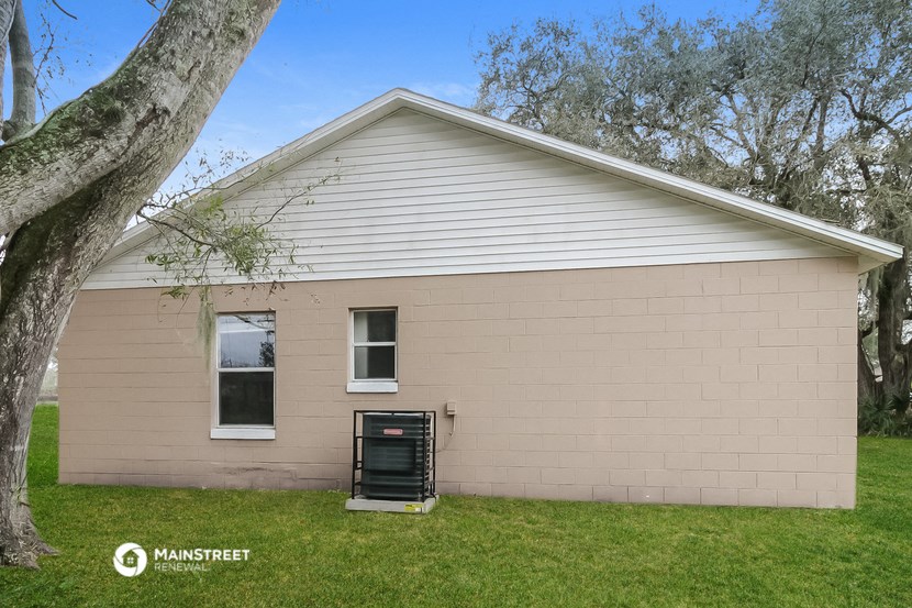 the front of a tan brick house with a tree
